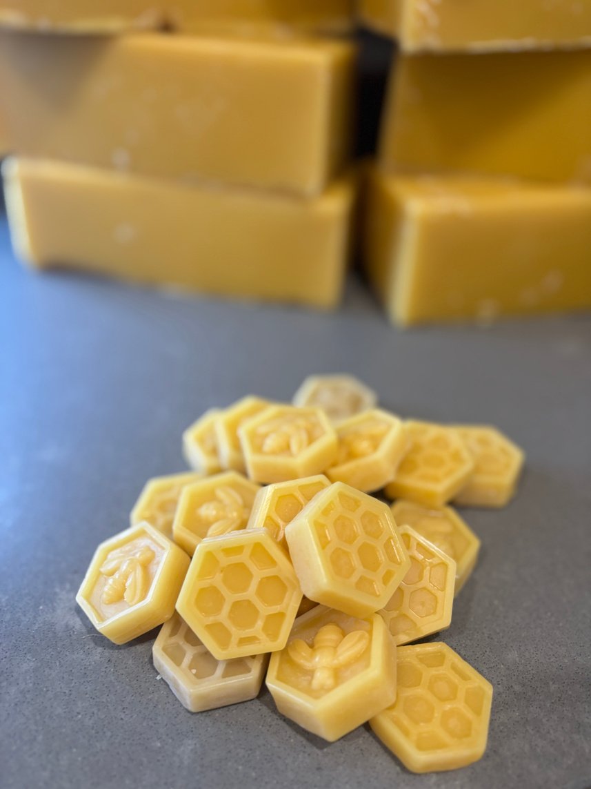 Hexagonal beeswax rounds stamped with a bee and honeycomb, blocks behind