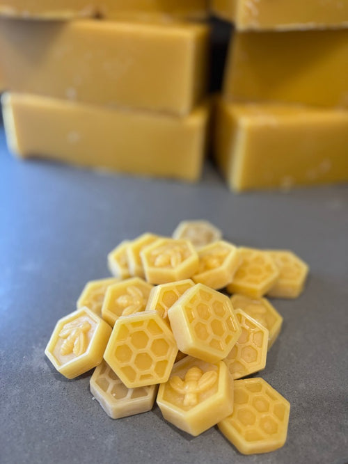 Hexagonal beeswax rounds stamped with a bee and honeycomb, blocks behind